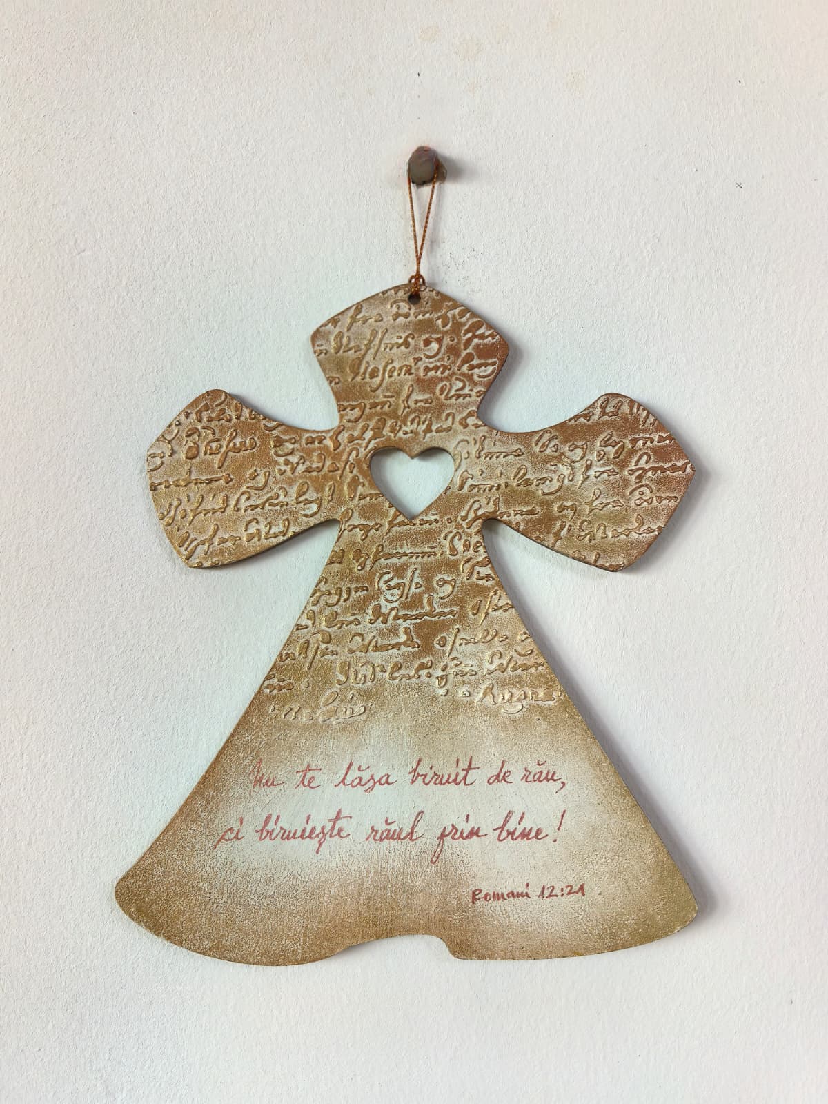 Obiect decorativ în formă de cruce cu mesaj: „Nu te lăsa biruit de rău, ci biruiește răul prin bine!”